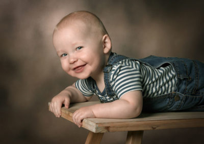 Børnefoto smilende dreng liggende på bænk