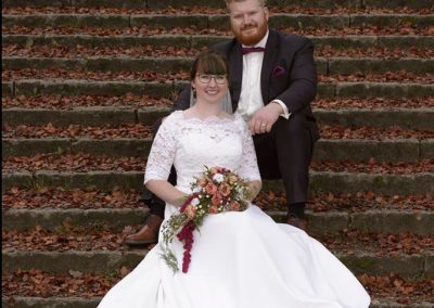 Bryllupsfoto brudepar på trappe med rød brune blade