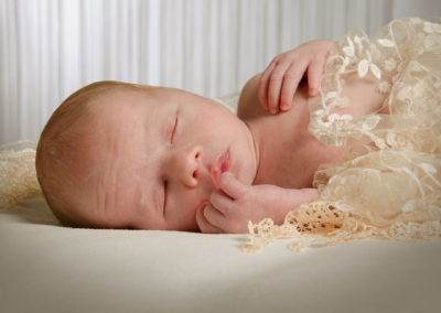 nyfødt foto baby sovende på ryggen med ansigtet frem